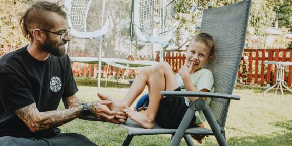 Playful interaction between a father and son in a sunny backyard setting.