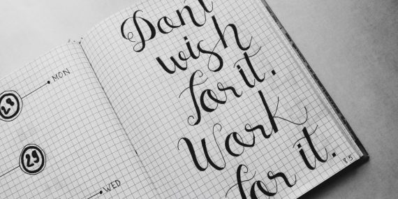 Close-up of motivational calligraphy on grid paper, inspiring message for productivity.